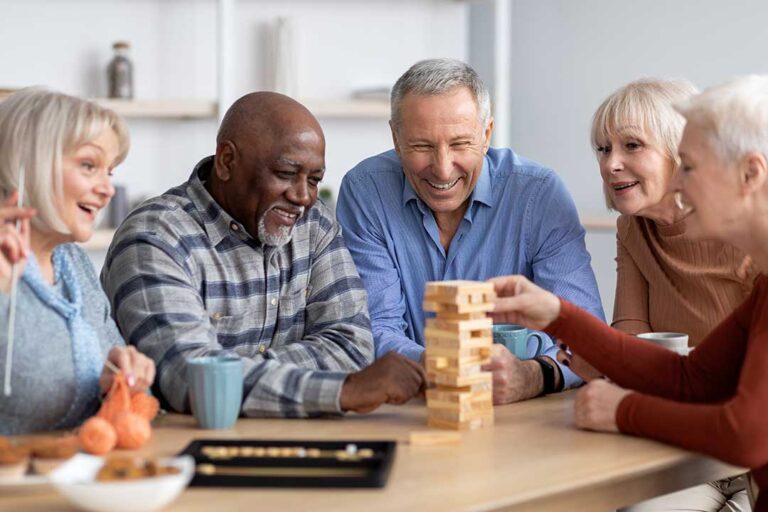 A small group of seniors chatting and laughing together in a bright communal living room.